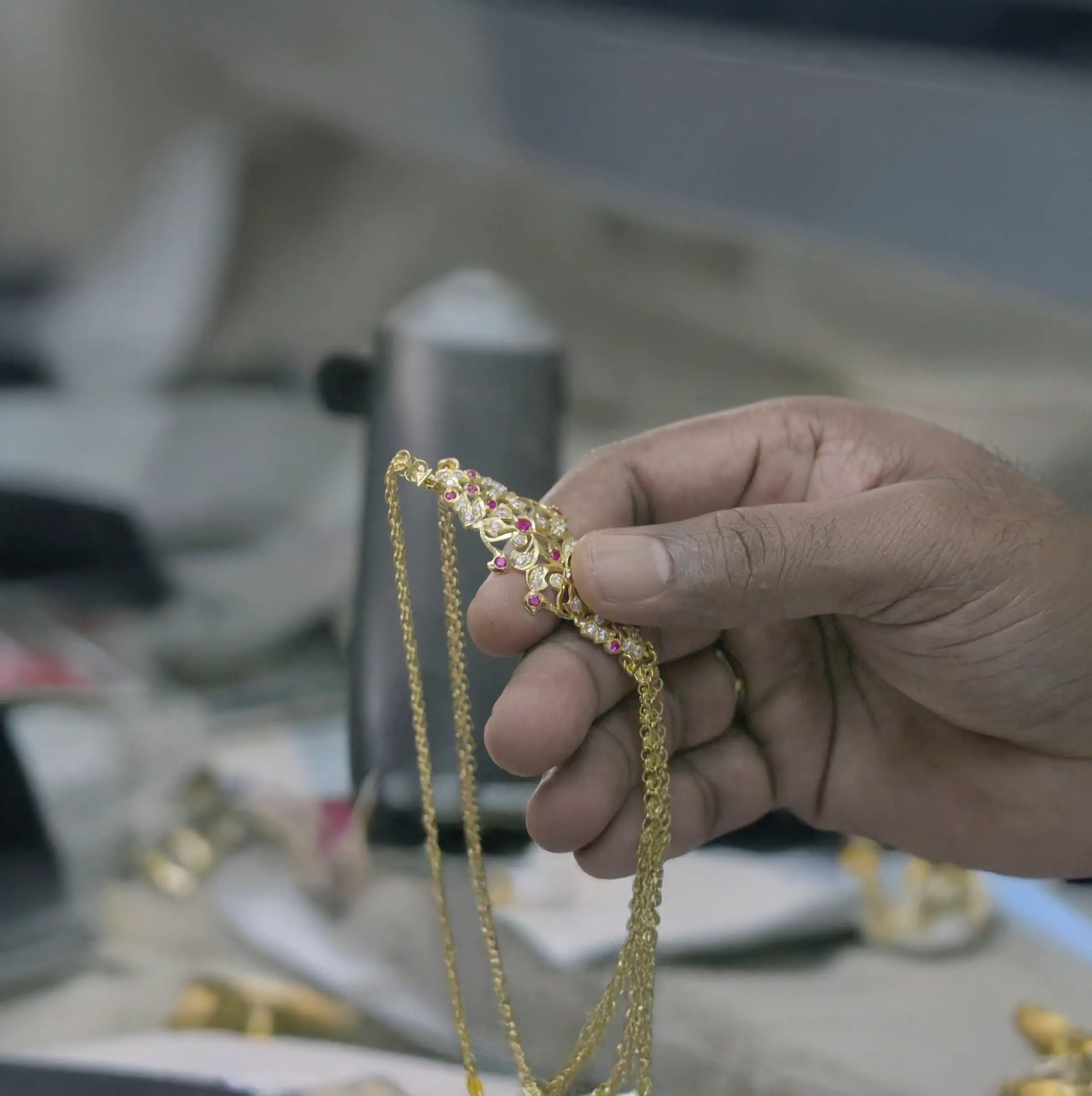 Hands cradle a luminous gold Indian necklace in the 'Made By Hand, Bound By Time' documentary, highlighting detailed craftsmanship.