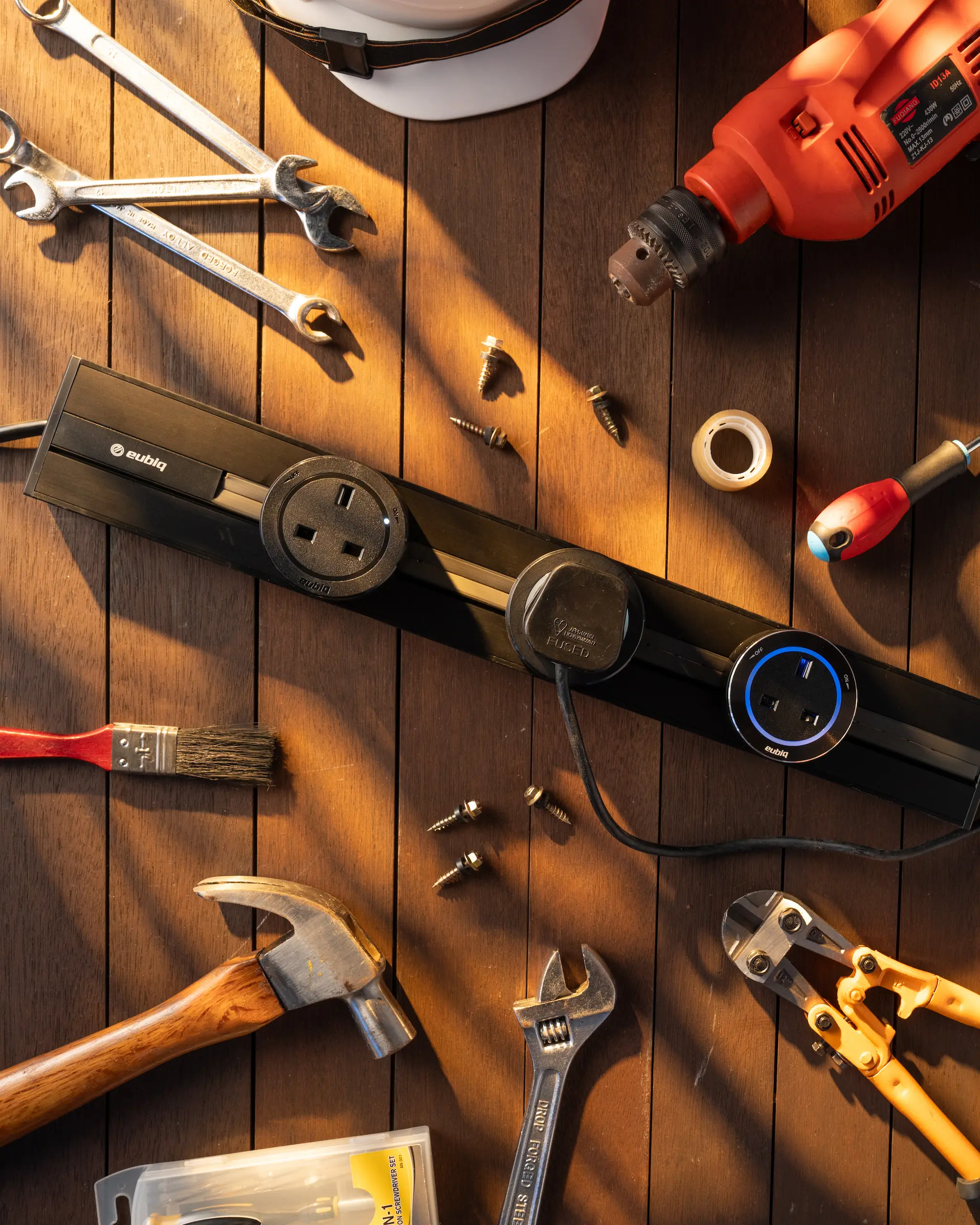 Eubiq adapter and power track laid out with handyman tools in warm golden-hour light for Father's Day.